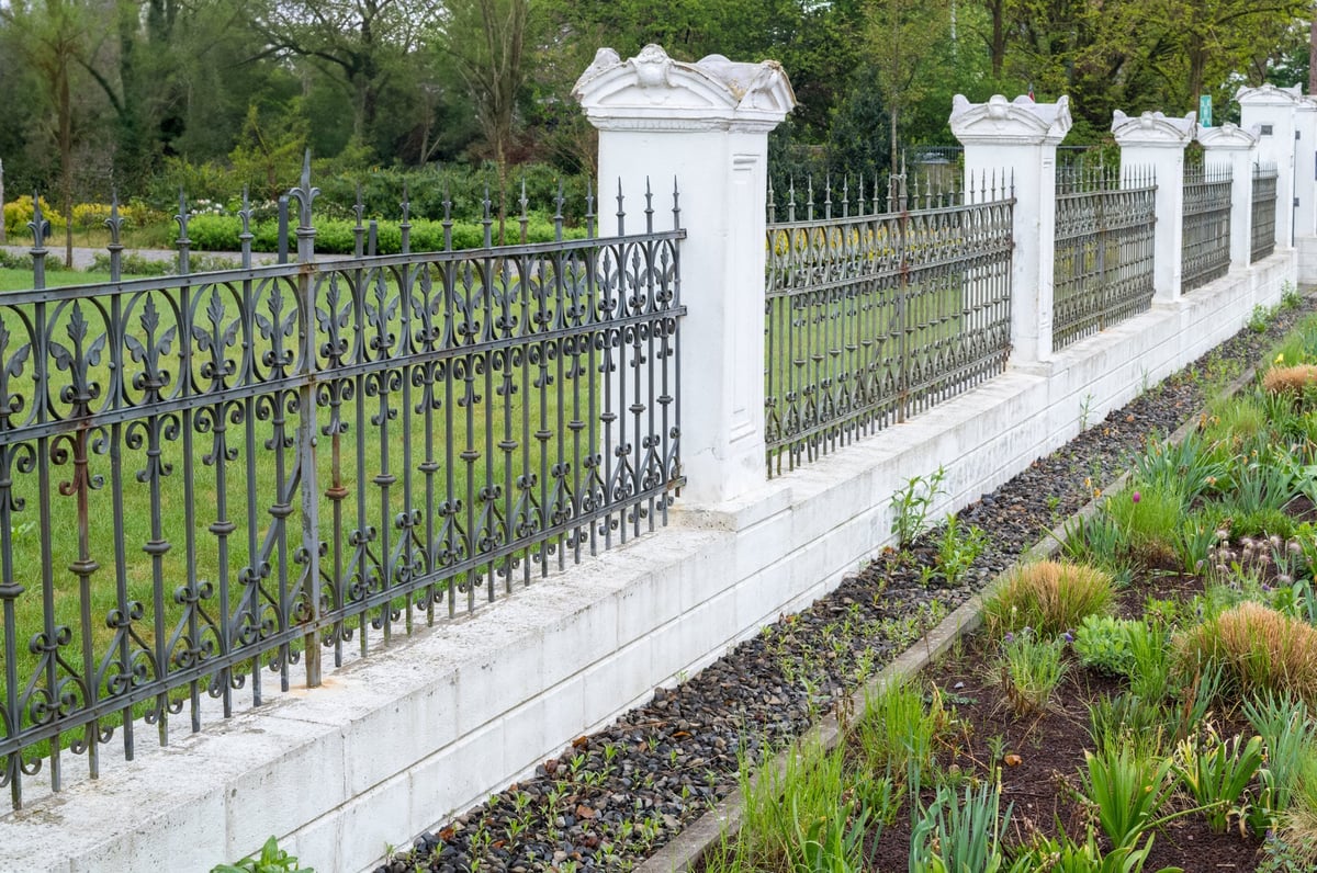 Ornate wrought-iron fence bordering a landscaped garden Brookshire TX