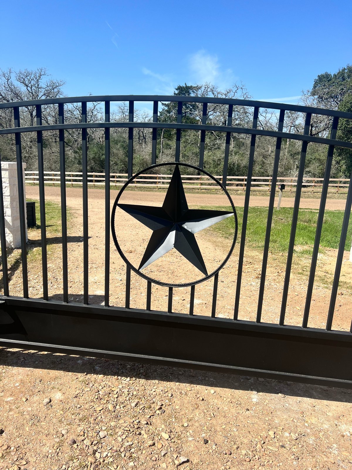 Black metal ranch gate with a Texas star cutout and open landscape