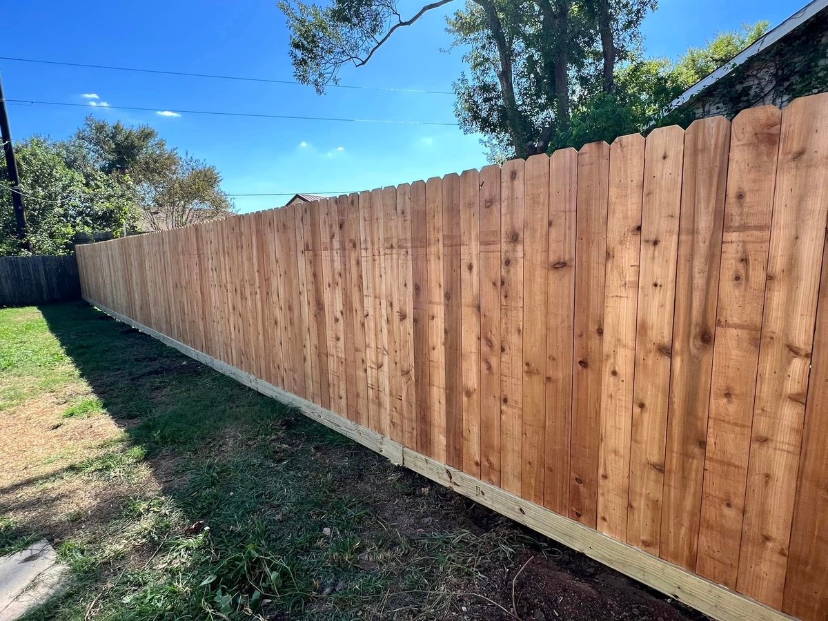 Tall new cedar privacy fence running through a grassy backyard in Brookshire TX