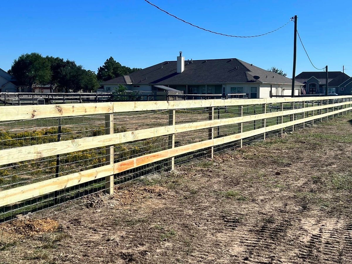 White ranch fencing enclosing a dirt arena at a Brookshire TX ranch property