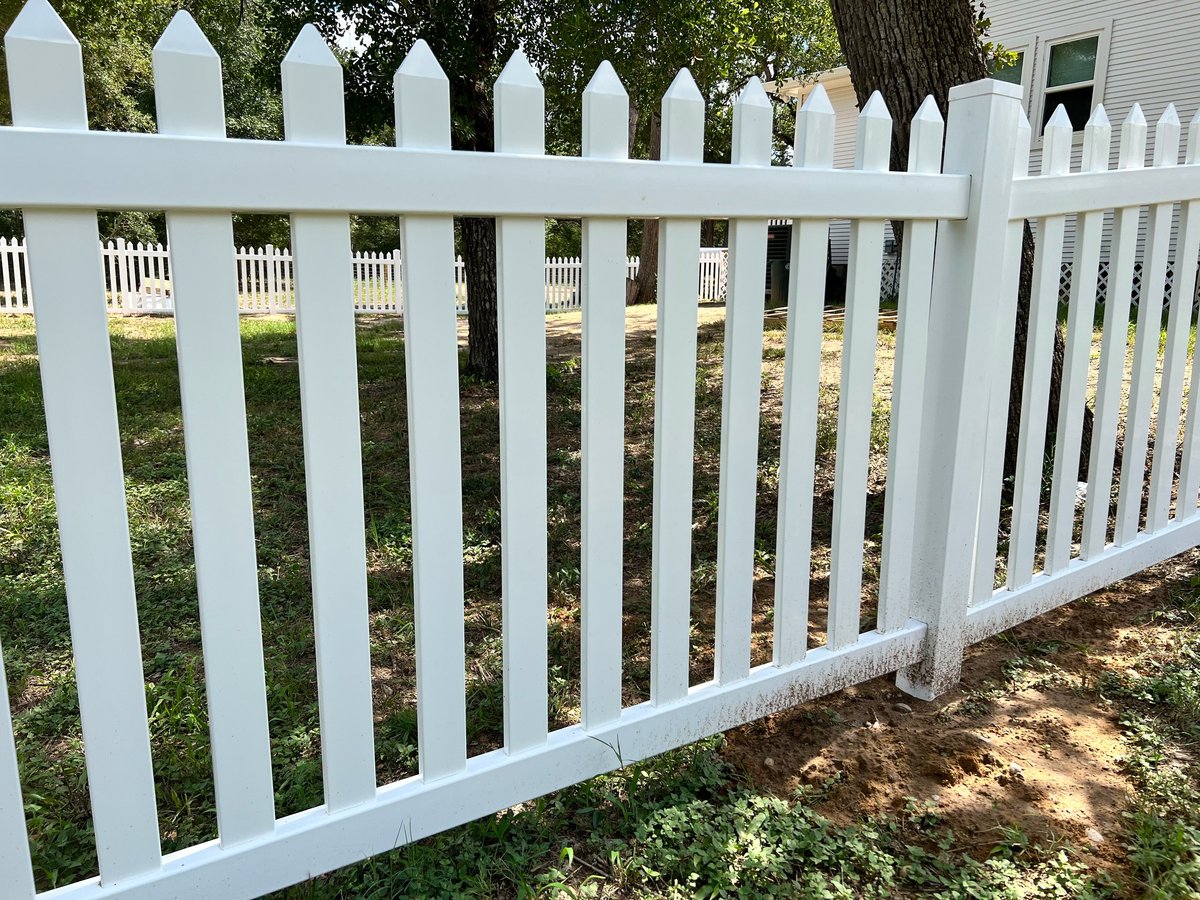 White picket fence with pointed tops in a residential yard Brookshire TX