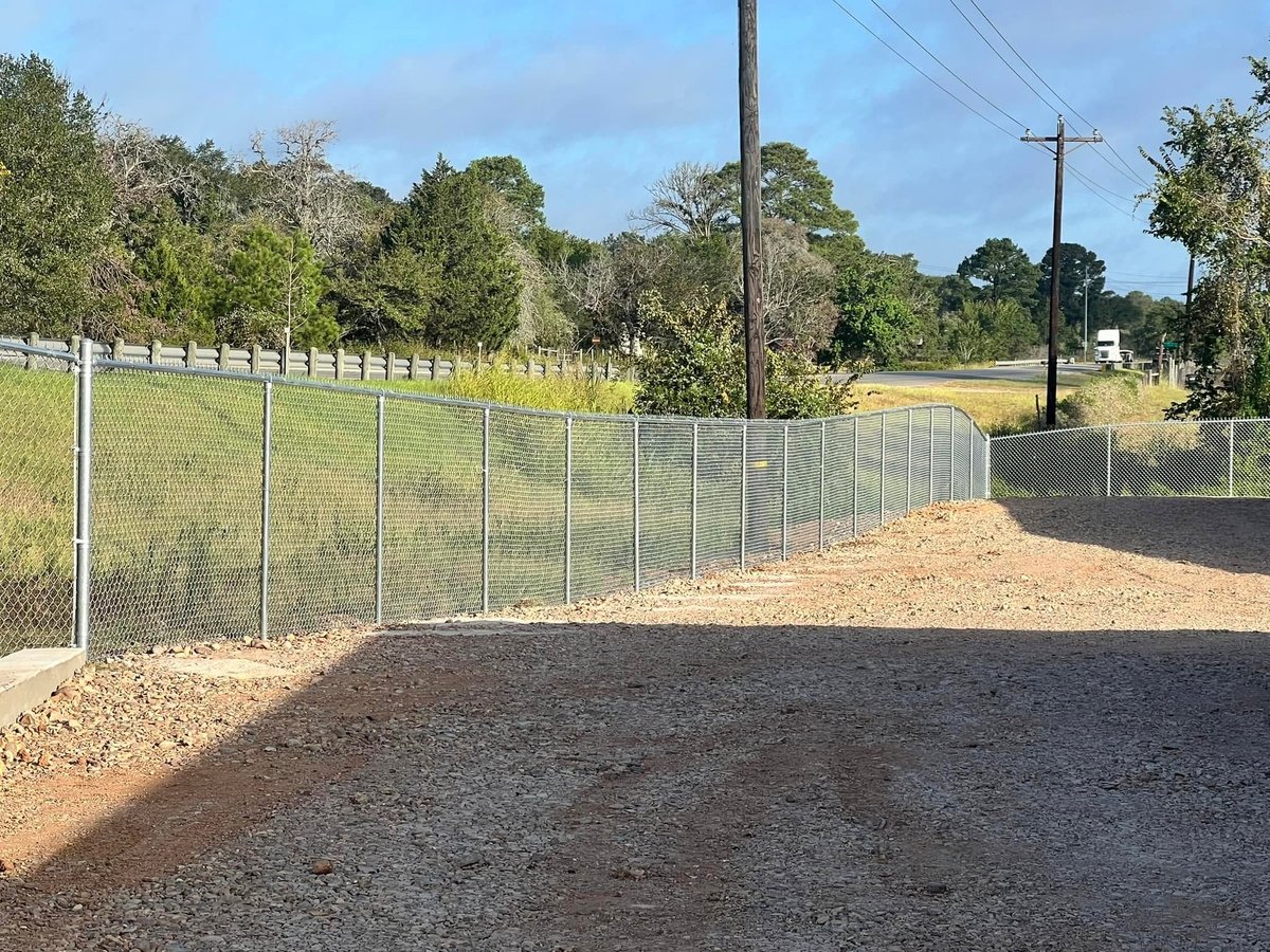Chain-link fence with metal gate installed at a rural gravel driveway in Brookshire TX